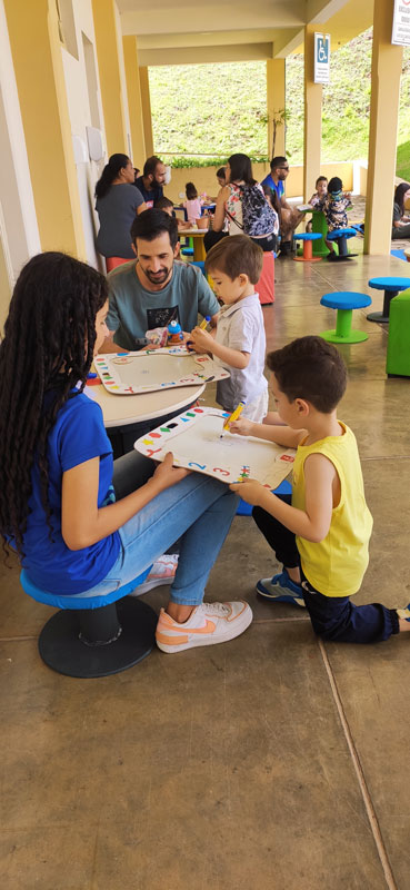 Pais e filhos brincando de colorir durante evento do Inatel