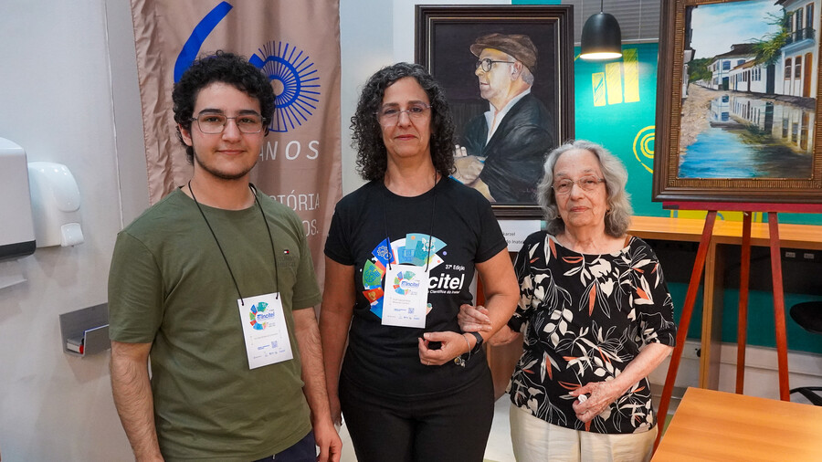 Da esquerda para a direita, o aluno Nicolas Mokarzel Carneiro, a professora Karina Perez Mokarzel Carneiro e a artista plástica Cidinha Perez Mokarzel. Na pintura, o professor Hélio Mokarzel.